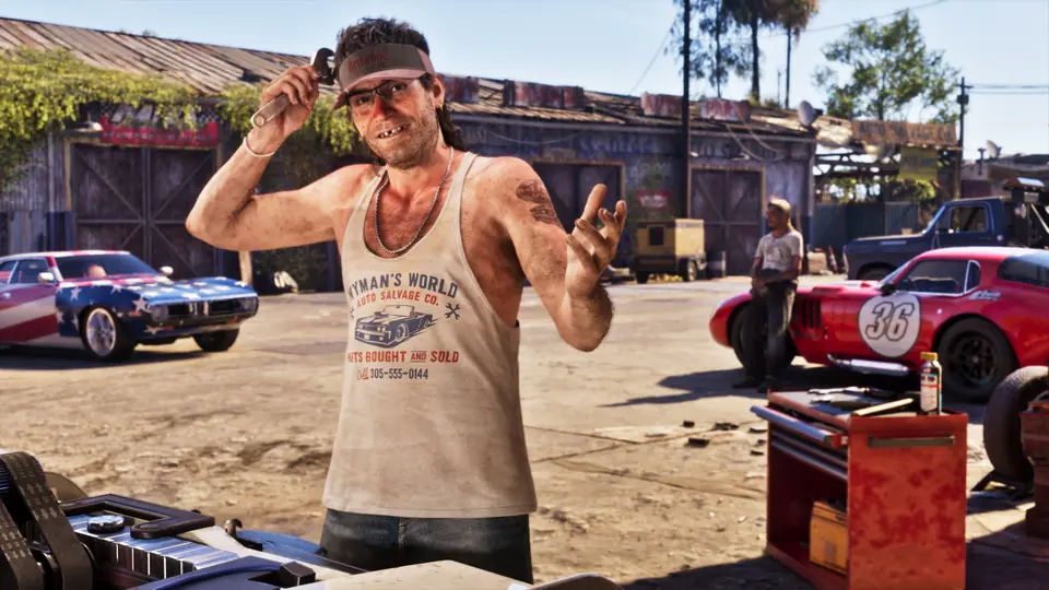 A mechanic waves in a yard of classic cars.